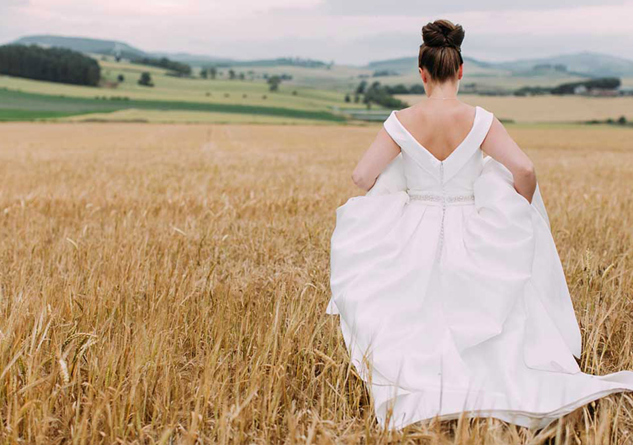 A bride walking through a field of corn