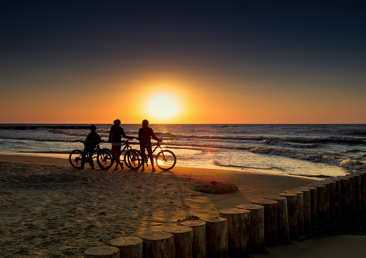 A family on a beach at sunset with their bikes