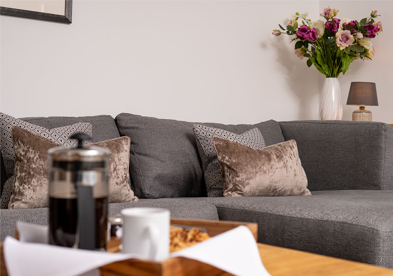 The cosy sofa with coffee and pastries on the table in Lodge 4 at Elderburn Luxury Lodges