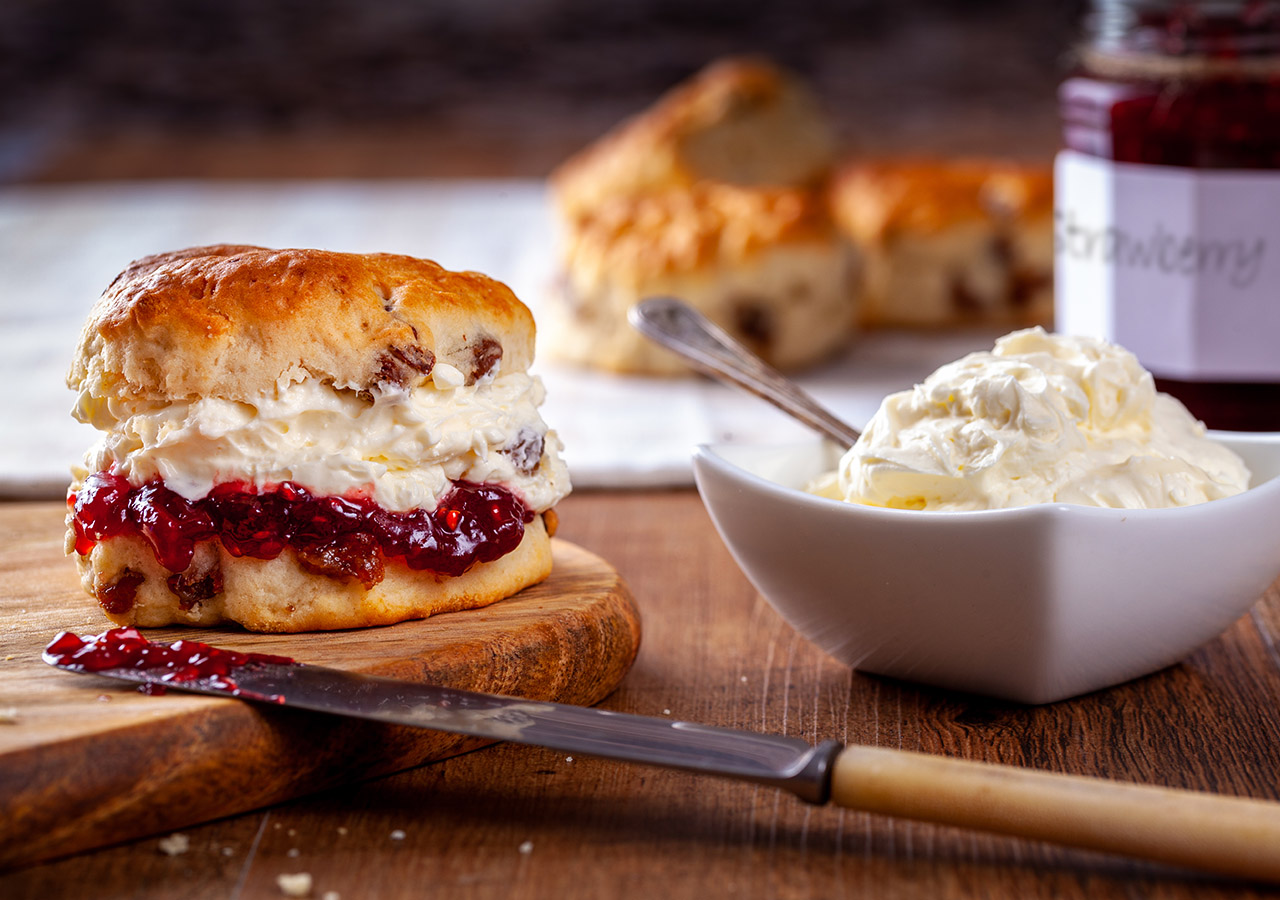 A tasty home-baked scone with strawberry jam and cream