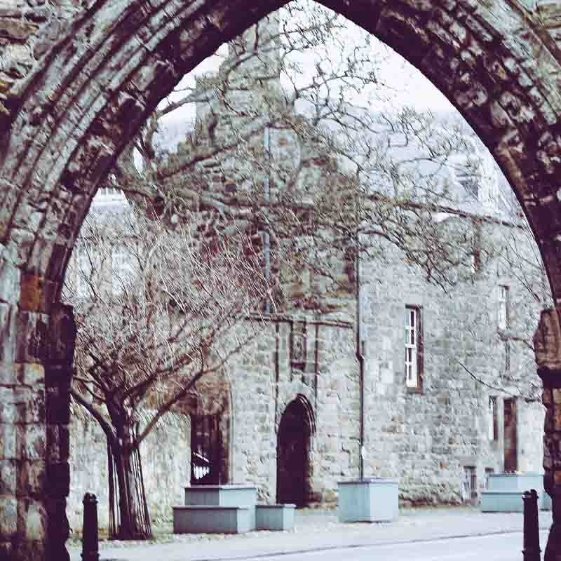 St Andrews on a snowy day through a stone arch.