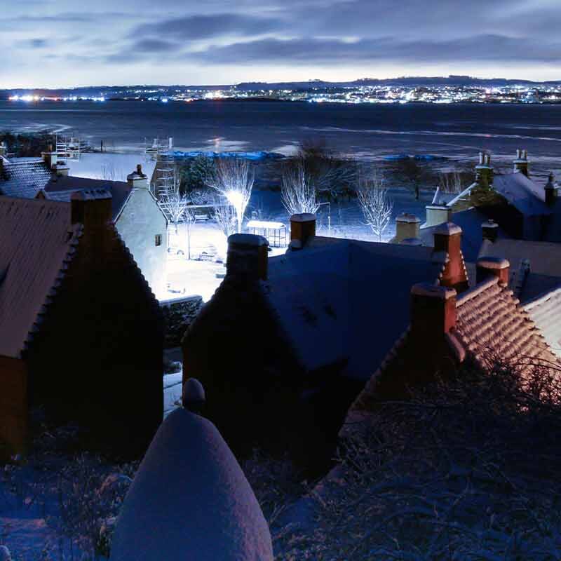 Culross in winter at night. White lights in a dark surrounding on buildings.